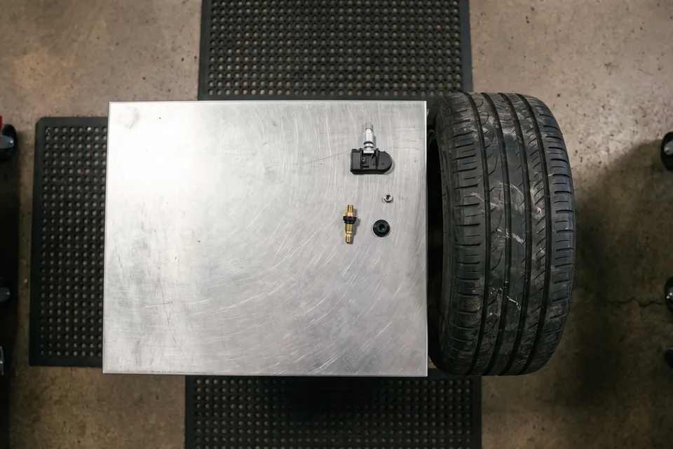 A TPMS sensor and service kit laid out beside a wheel